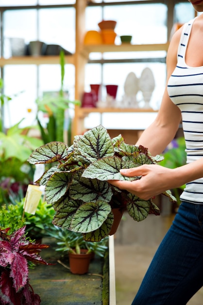 Una giovane donna adulta che lavora in un negozio di giardinaggio e che trasporta fiori