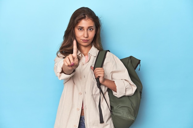 Young adventurer ready to explore with backpack showing number one with finger