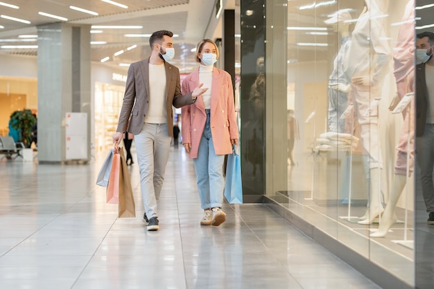 Young affectionate couple in casualwear walking in a mall