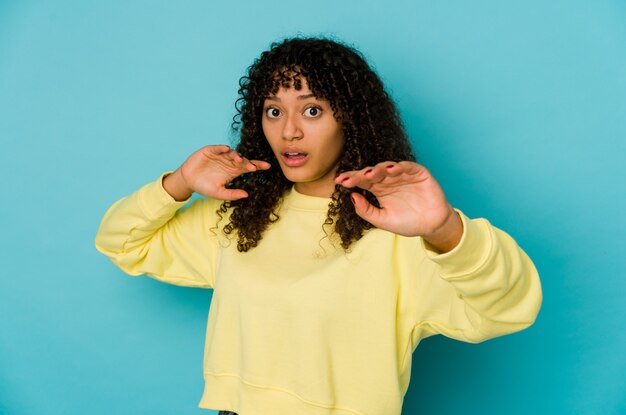 Young african american afro woman isolated being shocked due to an imminent danger