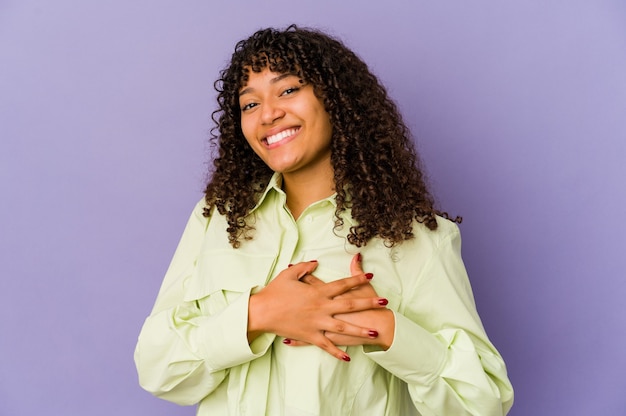 Young african american afro woman isolated has friendly expression, pressing palm to chest. Love concept.