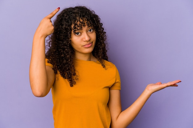 Young african american afro woman isolated holding and showing a product on hand.