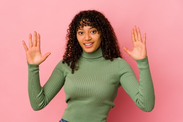 Young african american afro woman isolated holding something little with forefingers, smiling and confident.