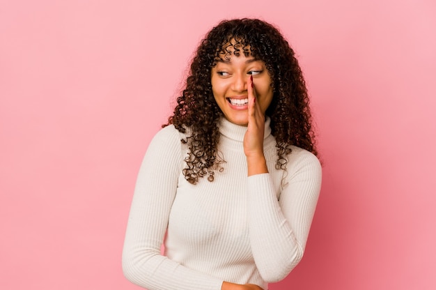 Young african american afro woman isolated is saying a secret hot braking news and looking aside