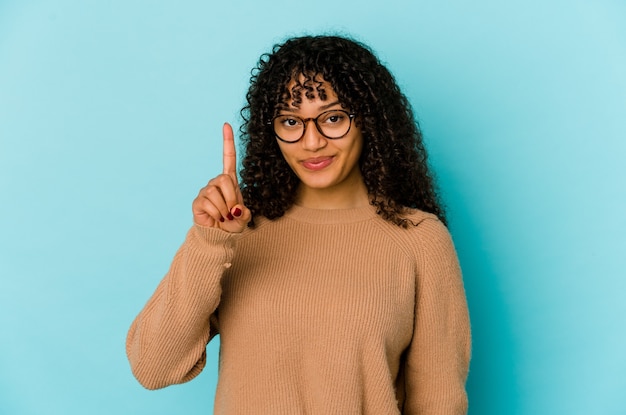 Giovane donna afroamericana afro isolata che mostra il numero uno con il dito.