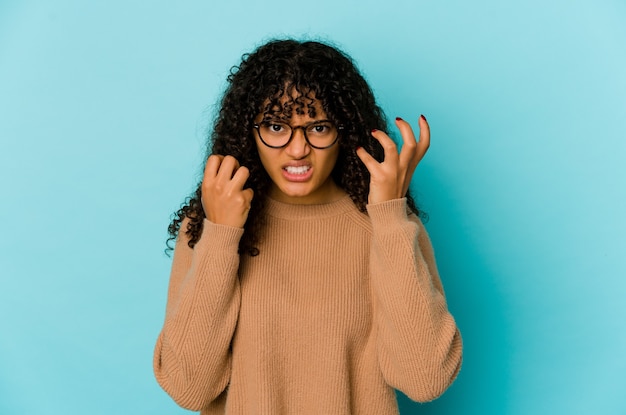 Young african american afro woman isolated upset screaming with tense hands.