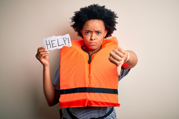 Foto giovane donna afroamericana afroamericana con i capelli ricci che indossa il giubbotto di salvataggio che tiene la carta di aiuto con il segno negativo della faccia arrabbiata che mostra antipatia con il concetto di rifiuto del pollice verso il basso