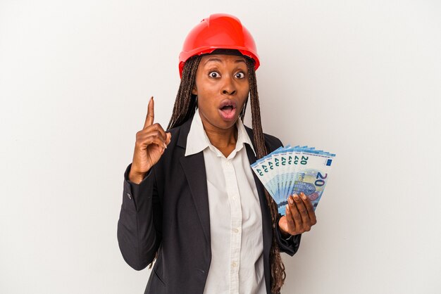 Young african american architect woman holding bills isolated on white background having an idea, inspiration concept.