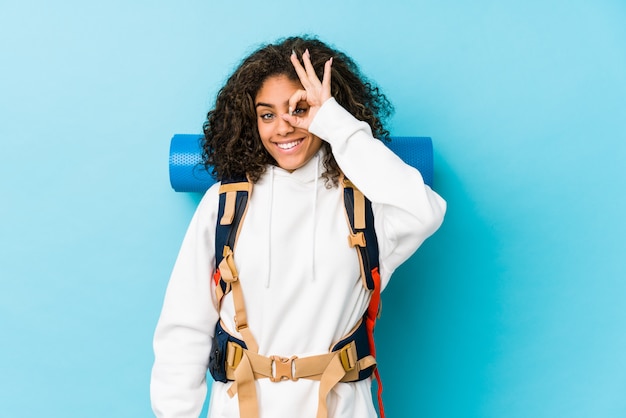 Young african american backpacker woman excited keeping ok gesture on eye.