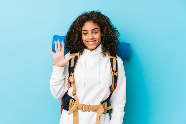 Young african american backpacker woman smiling cheerful showing number five with fingers.