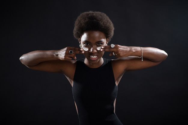 Young african american black woman applying by fingers white cream smear on her face with emotion