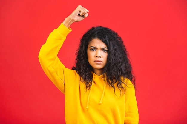 young african american black woman with raised fist isolated over red background