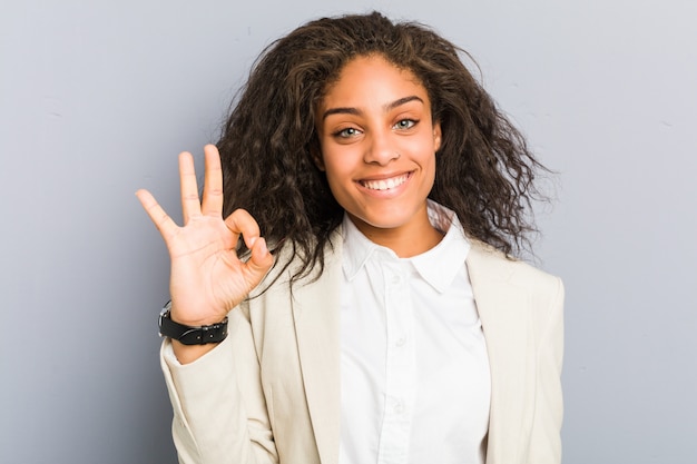 Young african american business woman cheerful and confident showing ok gesture.