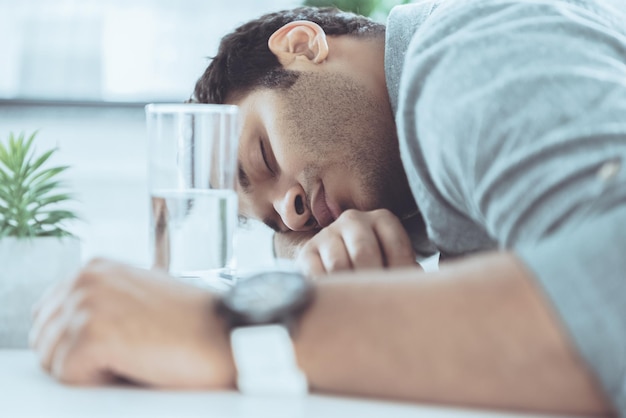 Young african american businessman sleeping on the table at modern office, business establishment