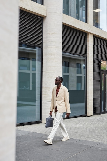Young african american businessman in white suit moving down sidewalk