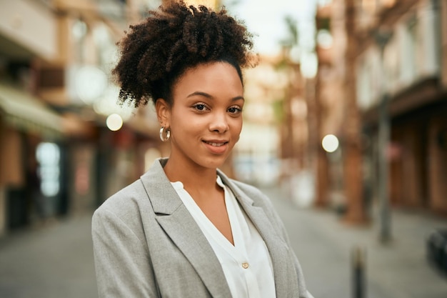 Молодая афроамериканская деловая женщина счастливо улыбается, стоя в городе