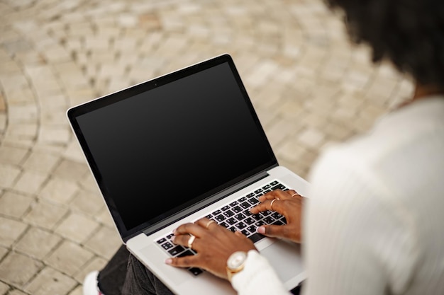 Young african american businesswoman working using laptop sitting on the bench in the city