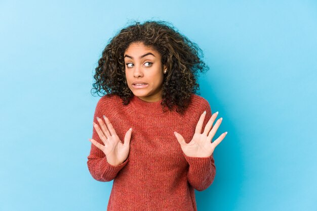 Giovane donna afroamericana dei capelli ricci che rifiuta qualcuno che mostra un gesto di disgusto.