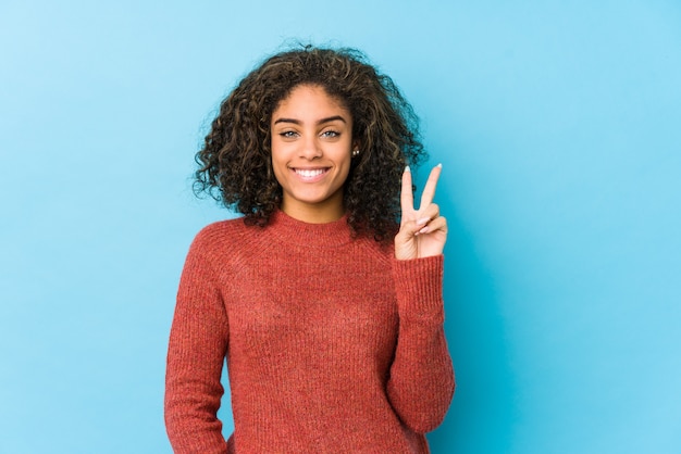 Young african american curly hair woman showing number two with fingers.