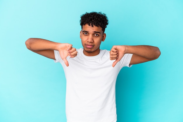 Young african american curly man isolated on blue showing a dislike gesture, thumbs down. Disagreement concept.