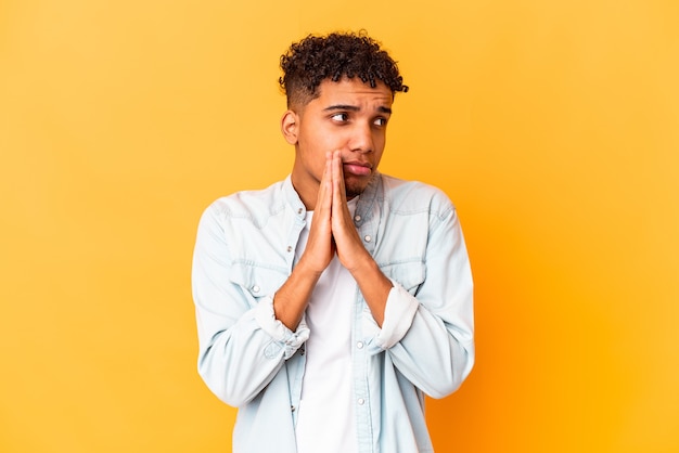 Young african american curly man isolated on purple praying, showing devotion, religious person looking for divine inspiration.