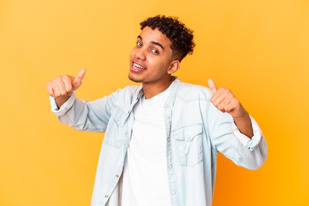 Young african american curly man isolated on purple raising both thumbs up, smiling and confident.