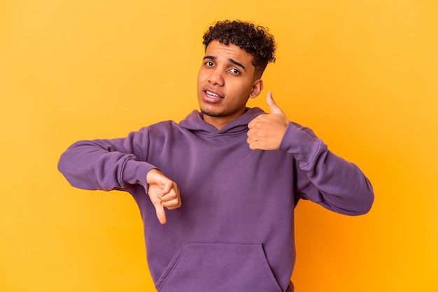 Young african american curly man isolated on purple showing thumbs up and thumbs down, difficult choose concept