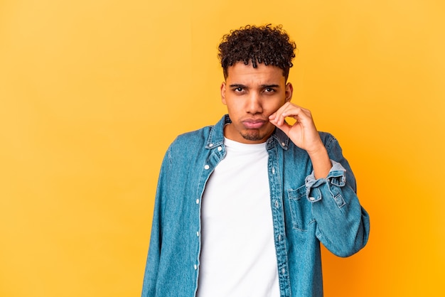 Young african american curly man isolated on purple with fingers on lips keeping a secret.