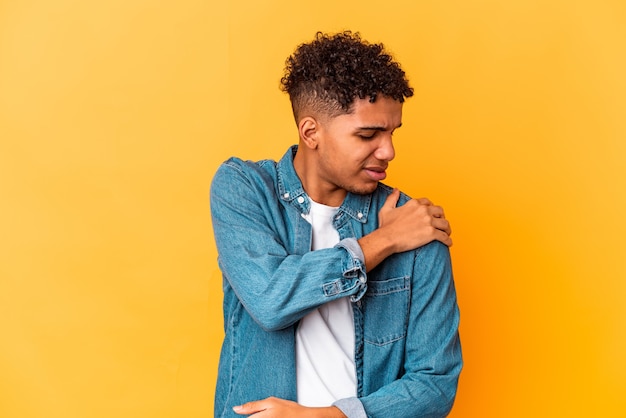 Young african american curly man on yellow having a shoulder pain.