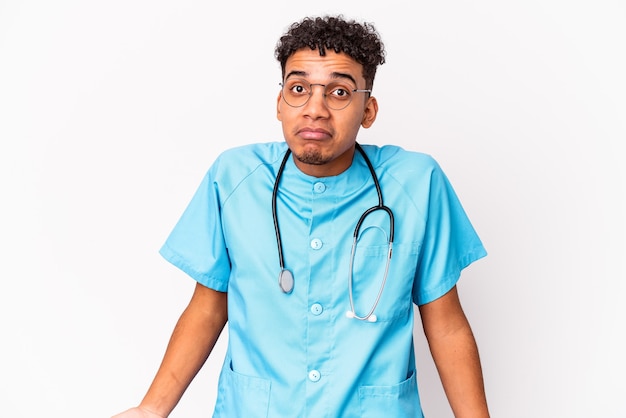 Young african american curly nurse man isolated shrugs shoulders and open eyes confused.