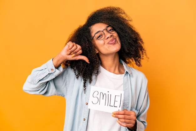 Young african american curly woman holding a smile message placard feels proud and self confident, example to follow.