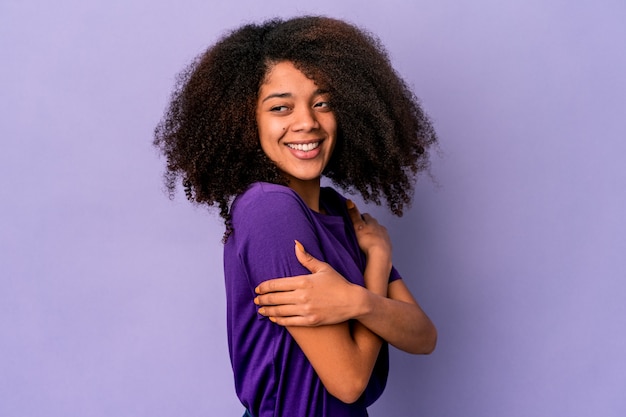 Young african american curly woman on purple laughing and having fun.