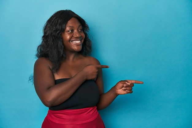 Young african american curvy woman excited pointing with forefingers away