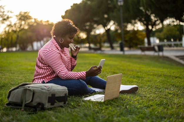 Young african american curvy woman having a lunch break in the park