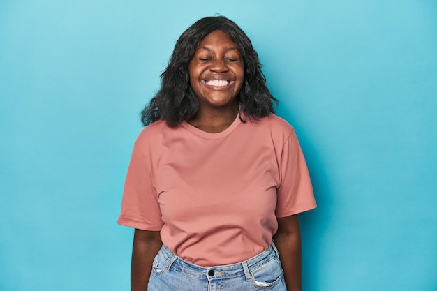 Photo young african american curvy woman laughs and closes eyes feels relaxed and happy