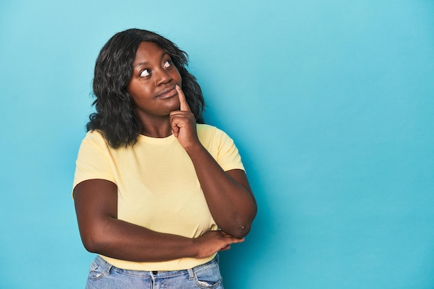 Young african american curvy woman looking sideways with doubtful and skeptical expression