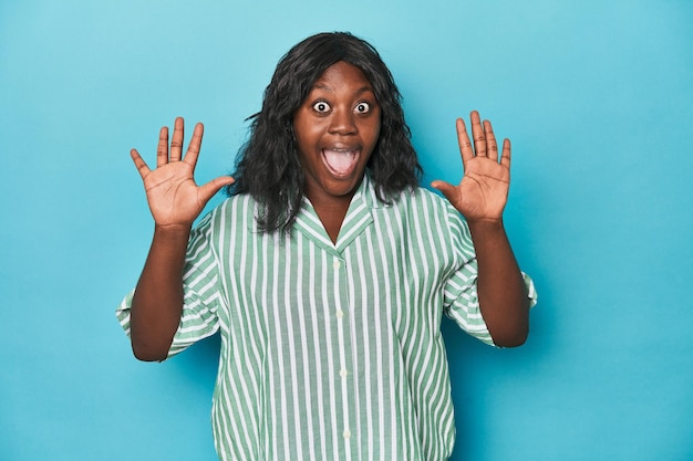 Young african american curvy woman receiving a pleasant surprise excited and raising hands