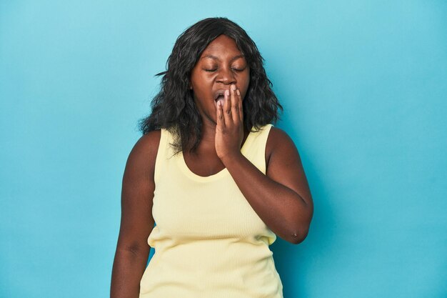 Young african american curvy woman yawning showing a tired gesture covering mouth with hand