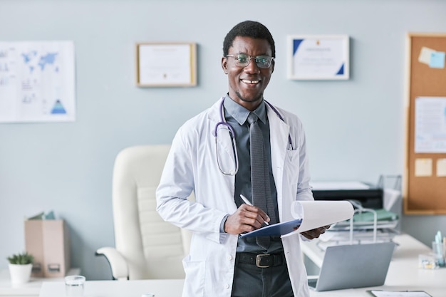 カメラに笑顔でクリップボードを保持している若いアフリカ系アメリカ人医師