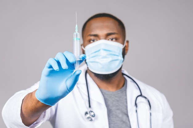 의료 마스크와 코로나 바이러스 백신 주사기를 들고 장갑을 착용하는 젊은 아프리카 계 미국인 의사