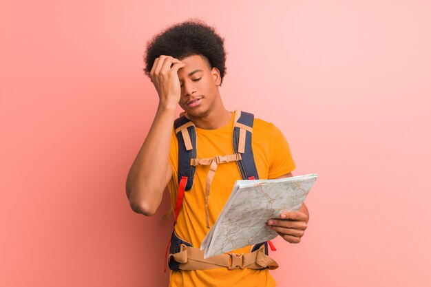 Young african american explorer man holding a map worried and overwhelmed