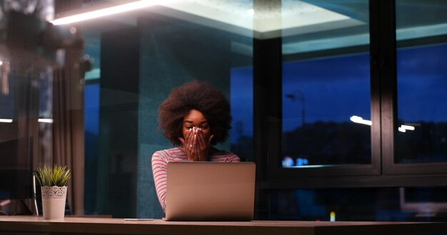 Photo young african american female entrepreneur freelancer working using a laptop in night coworking space