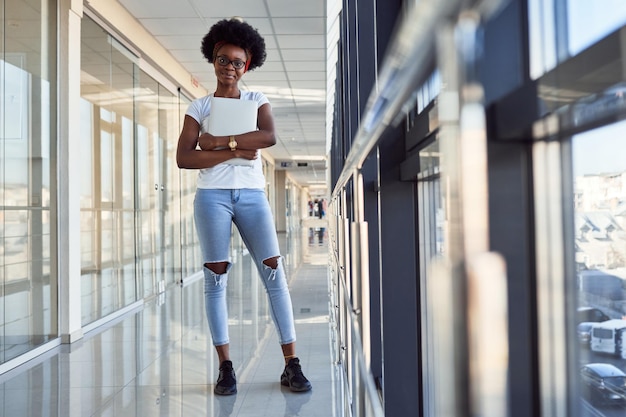 Young african american female passanger in casual clothes is in airport holding laptop.