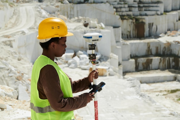 Young african american female surveyor choosing settings of theodolite