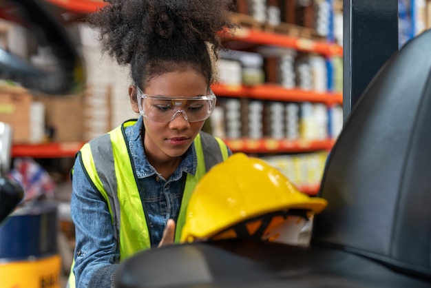 Young African American female worker forklift driver relaxing after work in factory warehouse