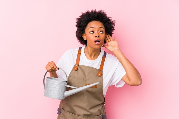 Young african american gardener woman trying to listening a gossip.