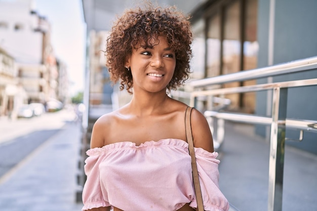 街に立っている幸せな笑みを浮かべて若いアフリカ系アメリカ人の女の子