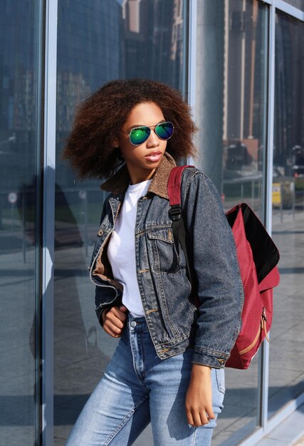 Young african american girl in sunglasses posing outdoors Dressed casual with short voluminous hair