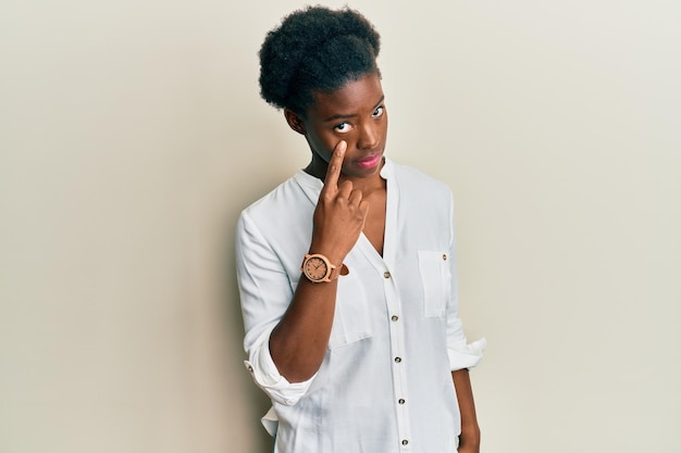 Young african american girl wearing casual clothes pointing to the eye watching you gesture suspicious expression