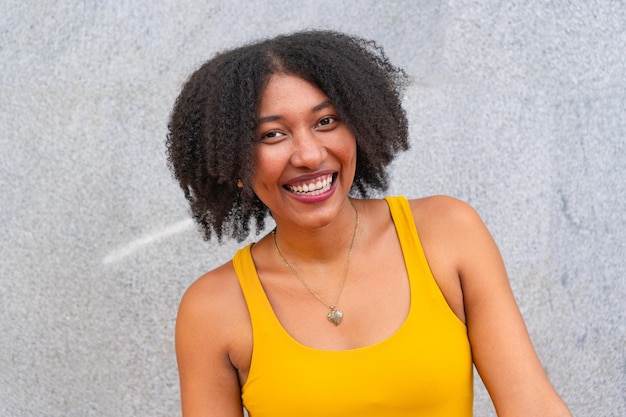 Young African American girl wears a yellow fashion garment with afro hair laughing